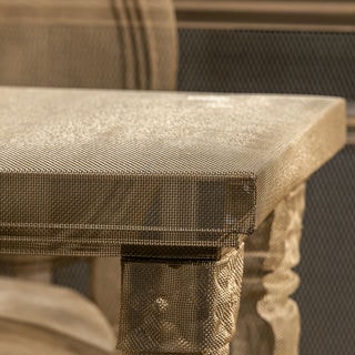 Detail image of a wire-mesh table and a chair, both transparent items in a DIOR showroom. Sculptures by David Begbie