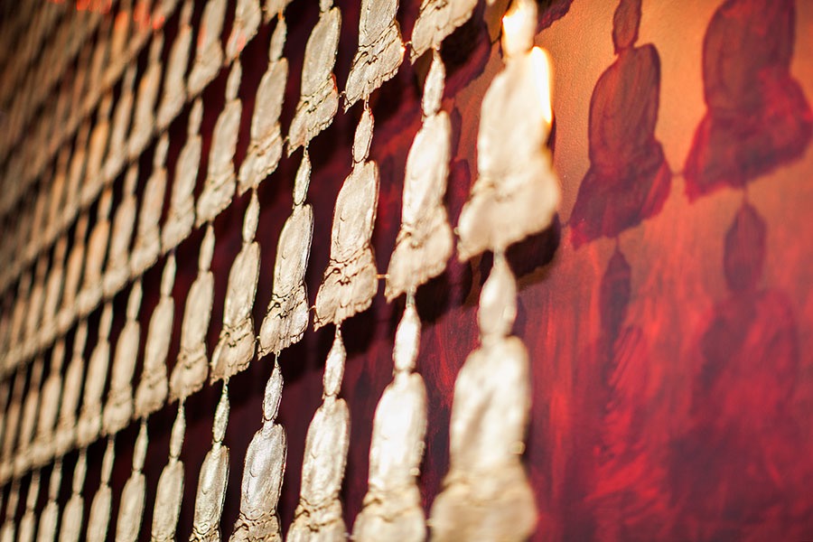Wall carpet made of semi-transparent Buddha figures. The image shows a detail and shadows
