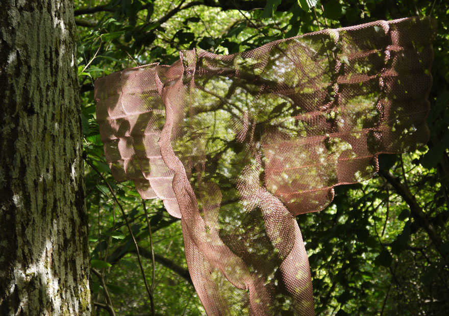 transparent angel sculpture in tree seen at Hannah Peschar Sculpture Garden