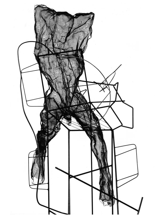 Large figure seated on an abstract steel construct. Artwork by David Begbie
