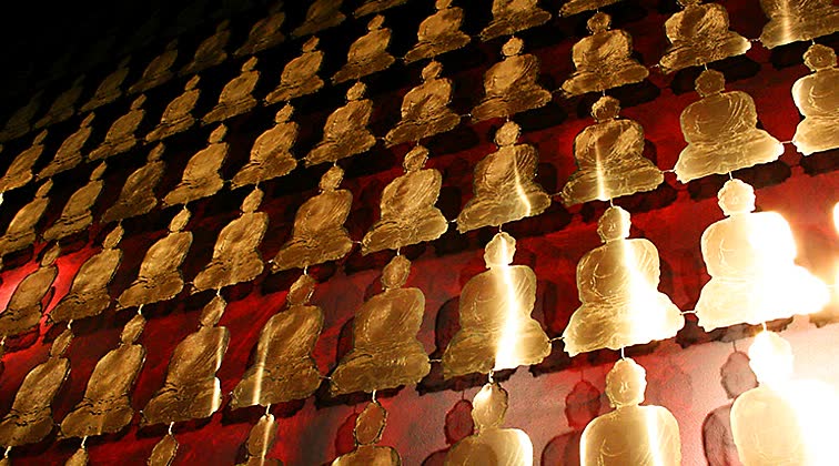 Wall curtain comprised of brass Buddha sculptures seen in London Buddha-Bar