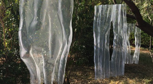 White abstract mesh sculptures presented in a garden