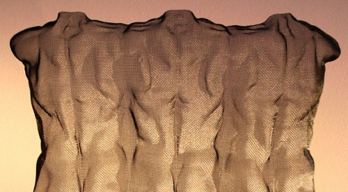 Detail of a modern steel sculpture in wire-mesh depicting three male back figures on orange background