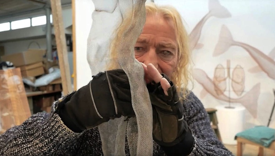 An artist in his studio is sculpting a wired figure
